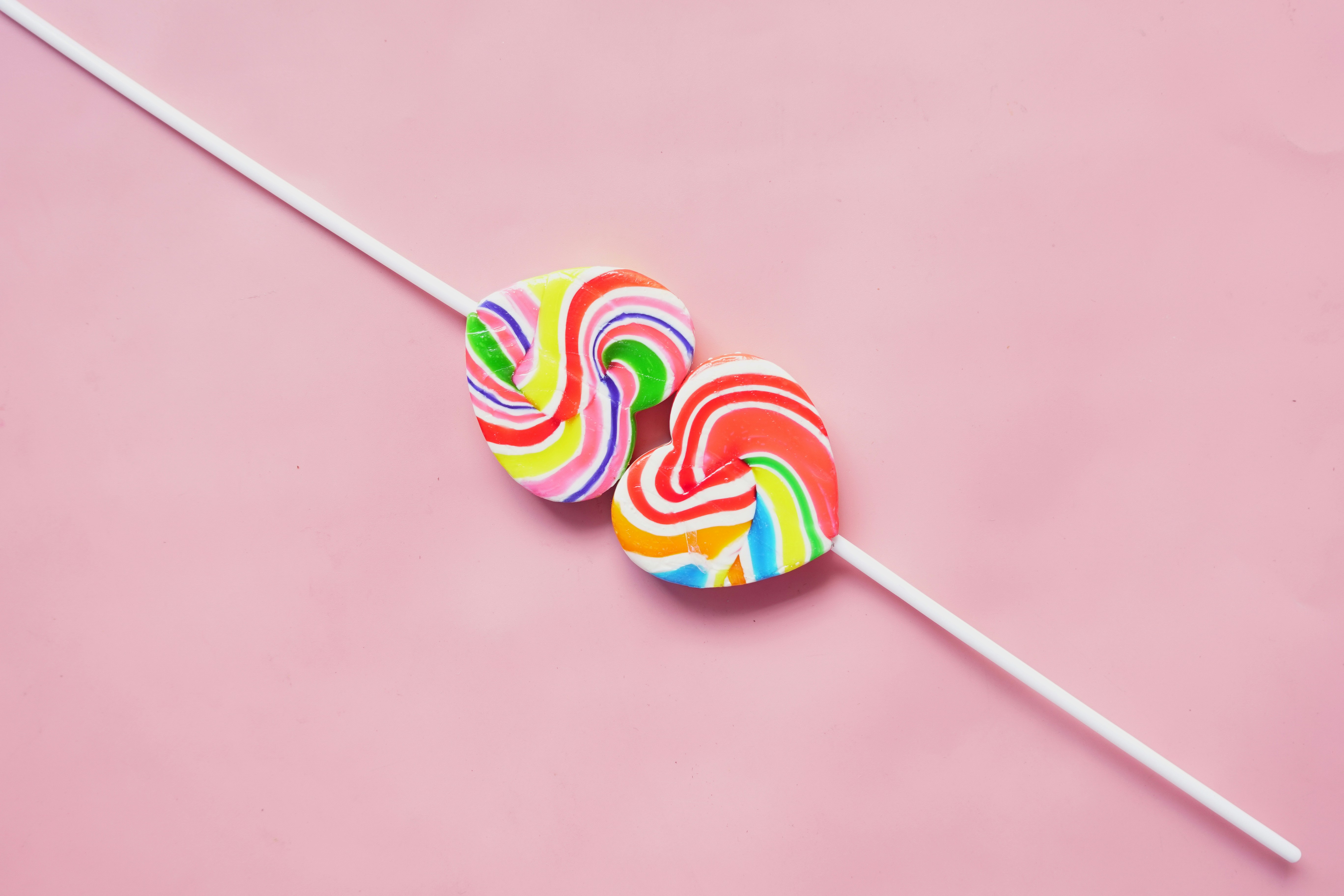 two lollipops sitting on top of a pink surface